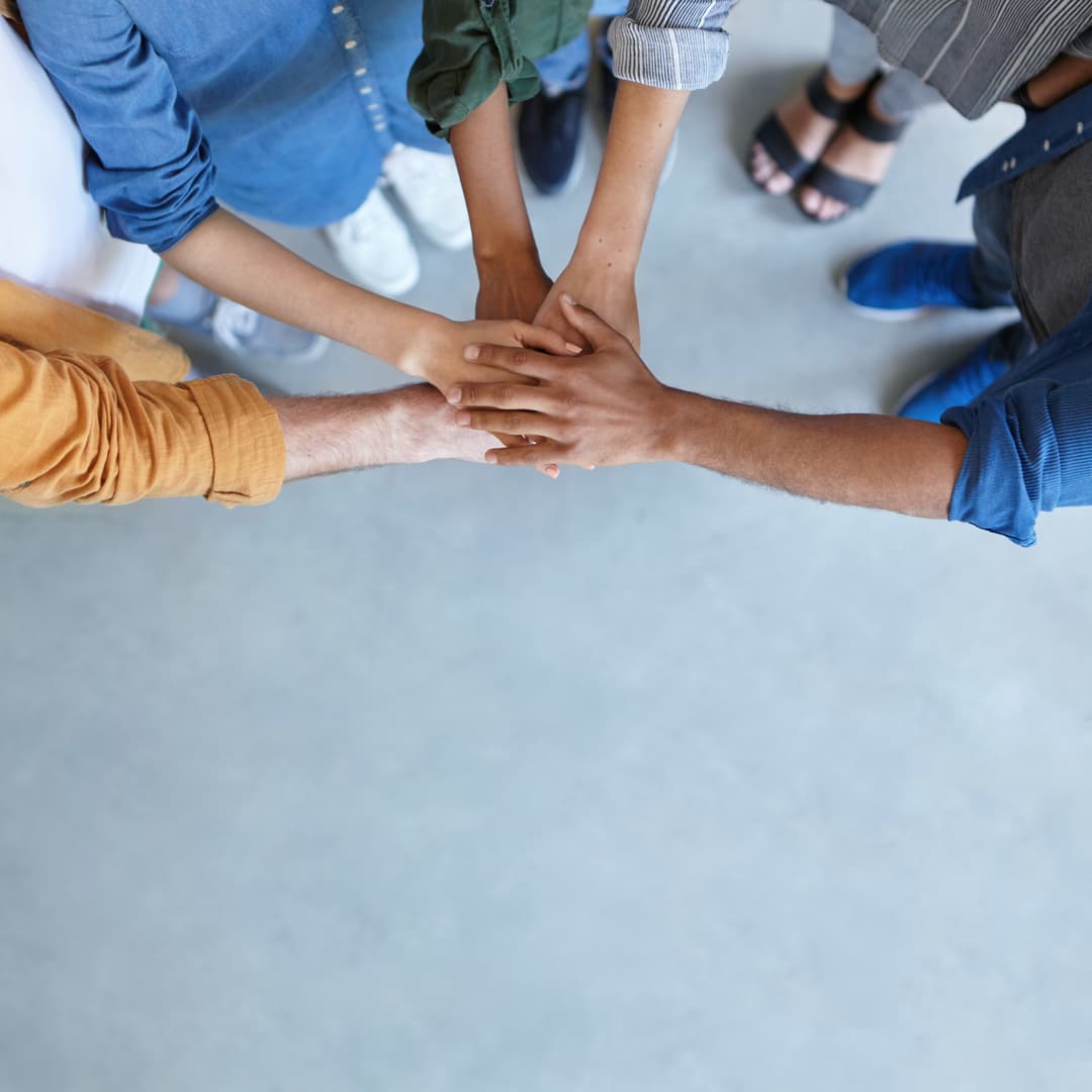 Grupo de pessoas com as mãos unidas em sinal de união e colaboração.